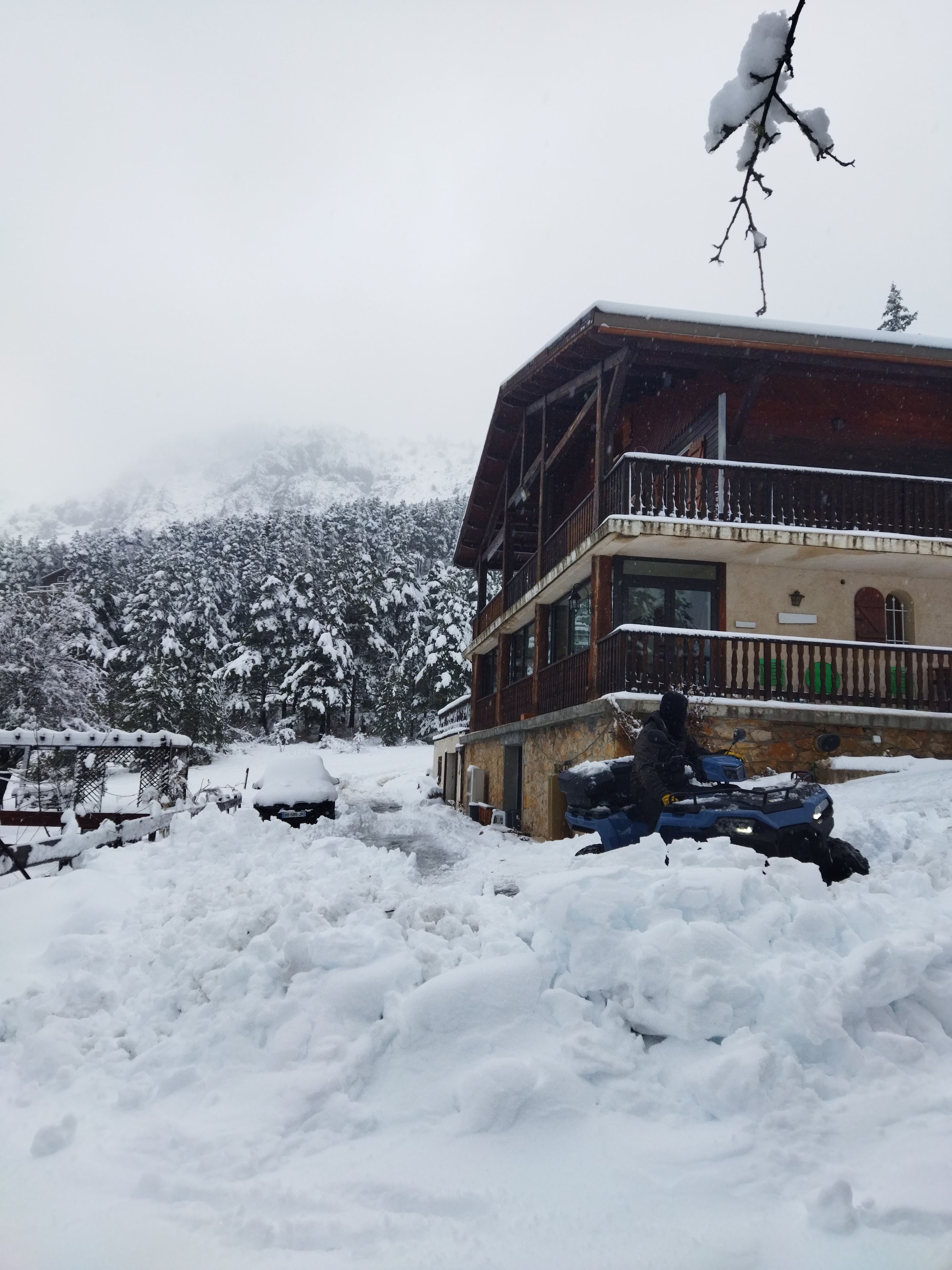 A multi-story building with a balcony, surrounded by snow-covered ground and trees.
