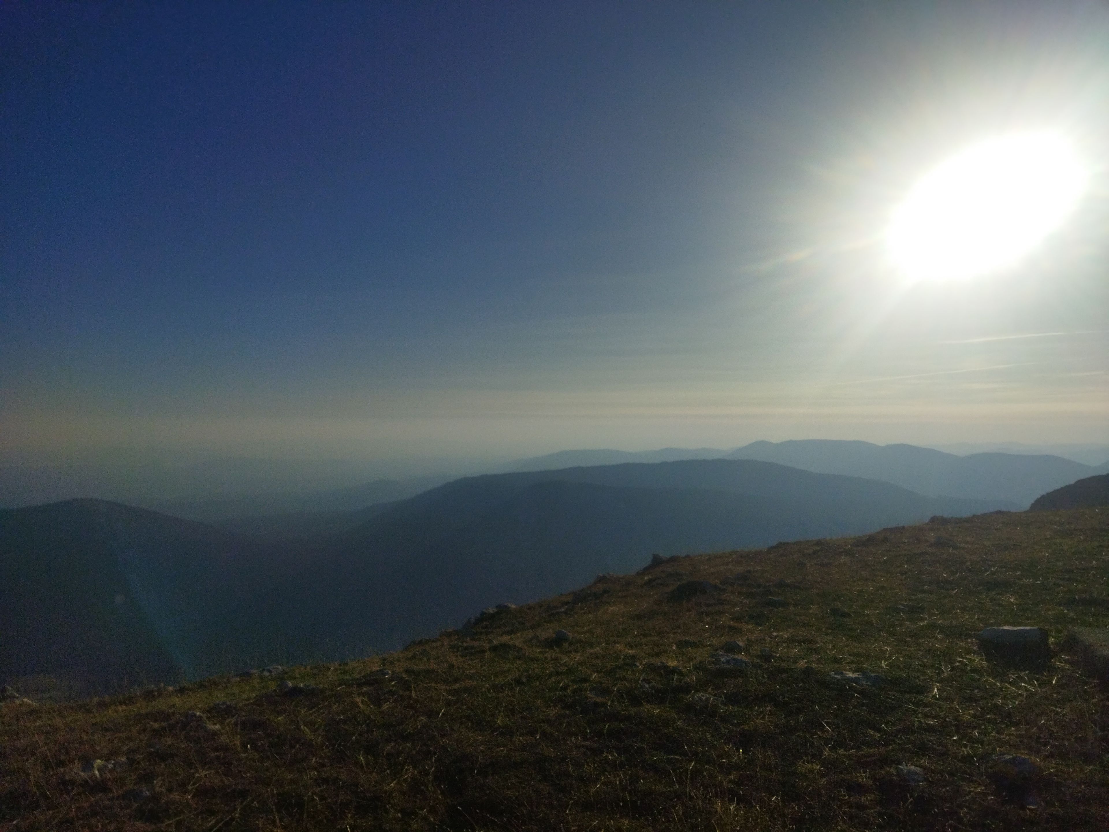 A mountainous landscape with a clear sky and the sun shining.