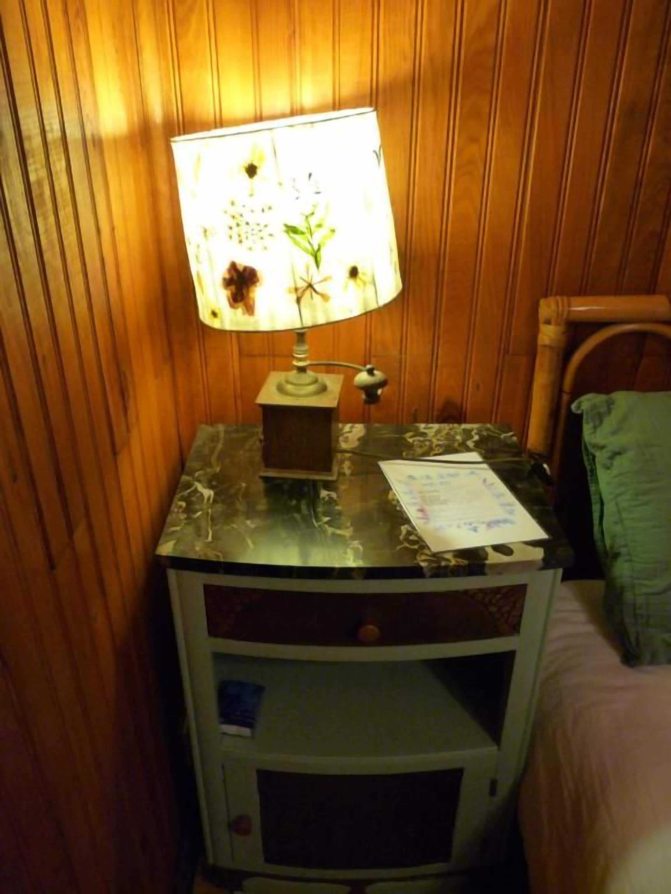 A bedside table with a lamp, a notepad, and a green towel.