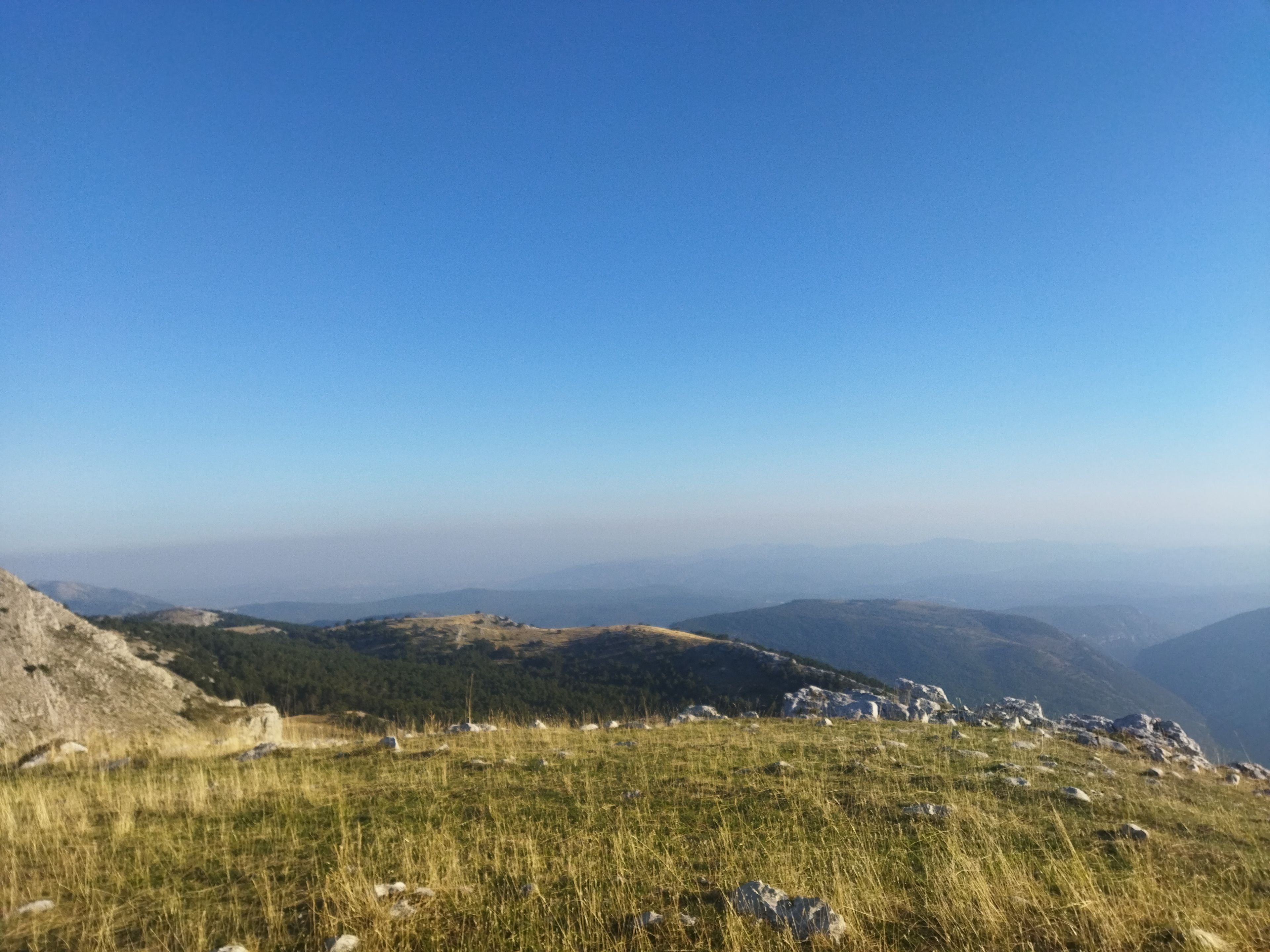 Un paisaje montañoso con terreno cubierto de hierba y afloramientos rocosos.