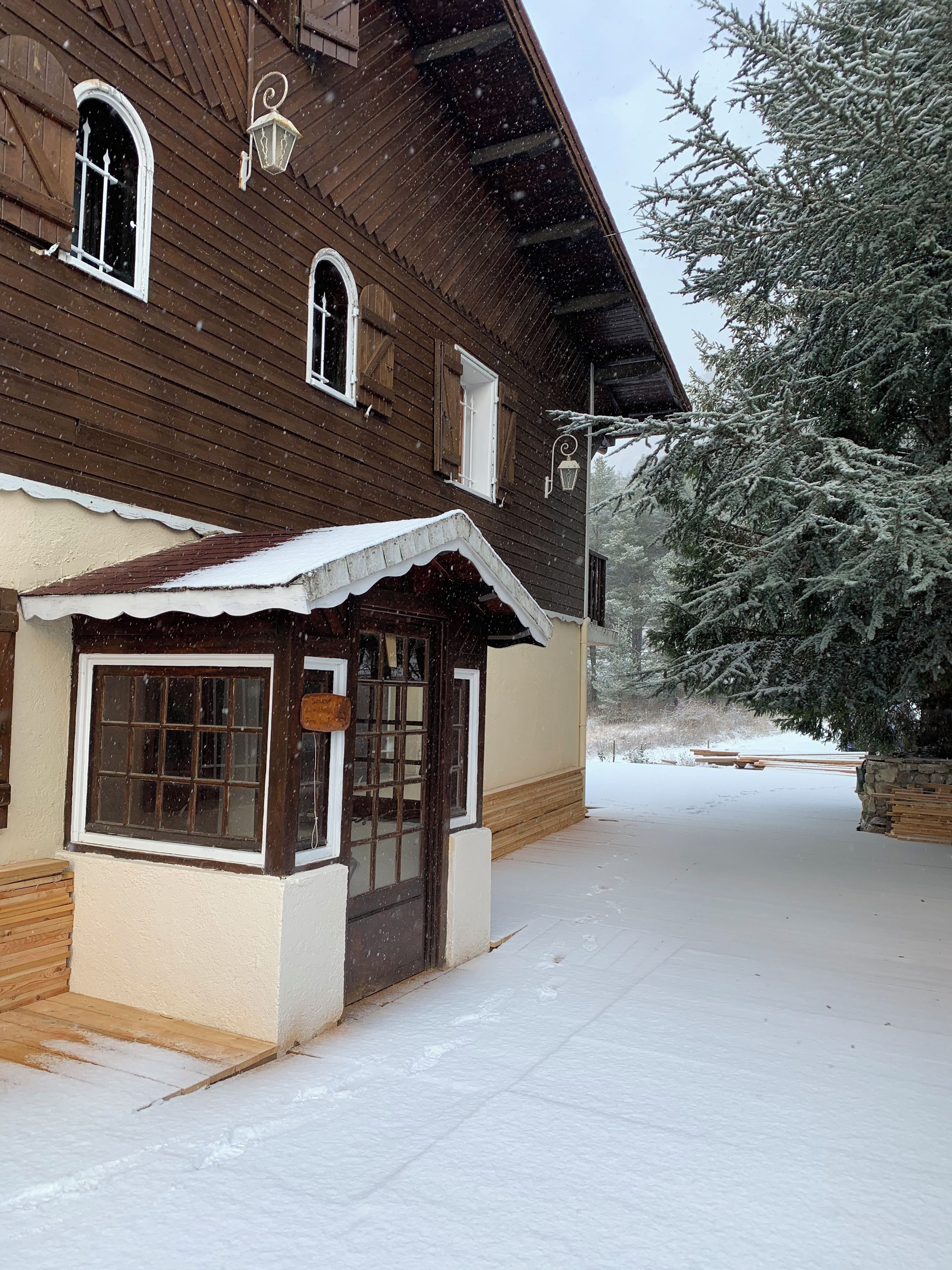 Un edificio de madera con techo nevado y un pequeño porche.