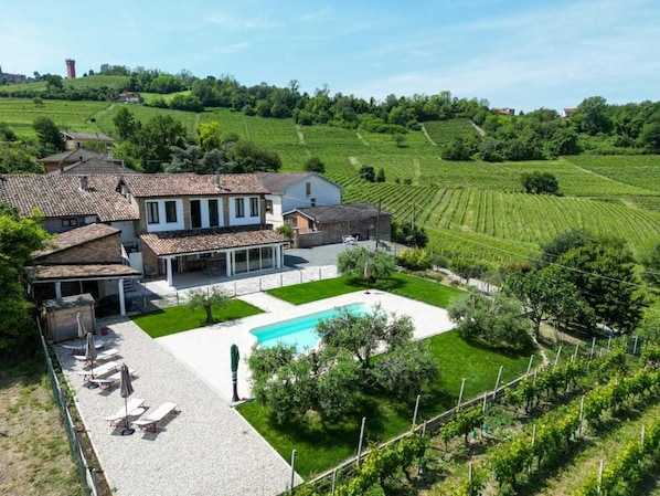 Una villa con piscina, viñedo y zona exterior cubierta.