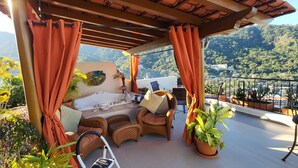 Terraço no telhado com hidromassagem, móveis de vime e plantas em vasos.