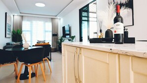 Et moderne køkken med marmorbordplade, en vinflaske og et spiseområde med stole og et bord.