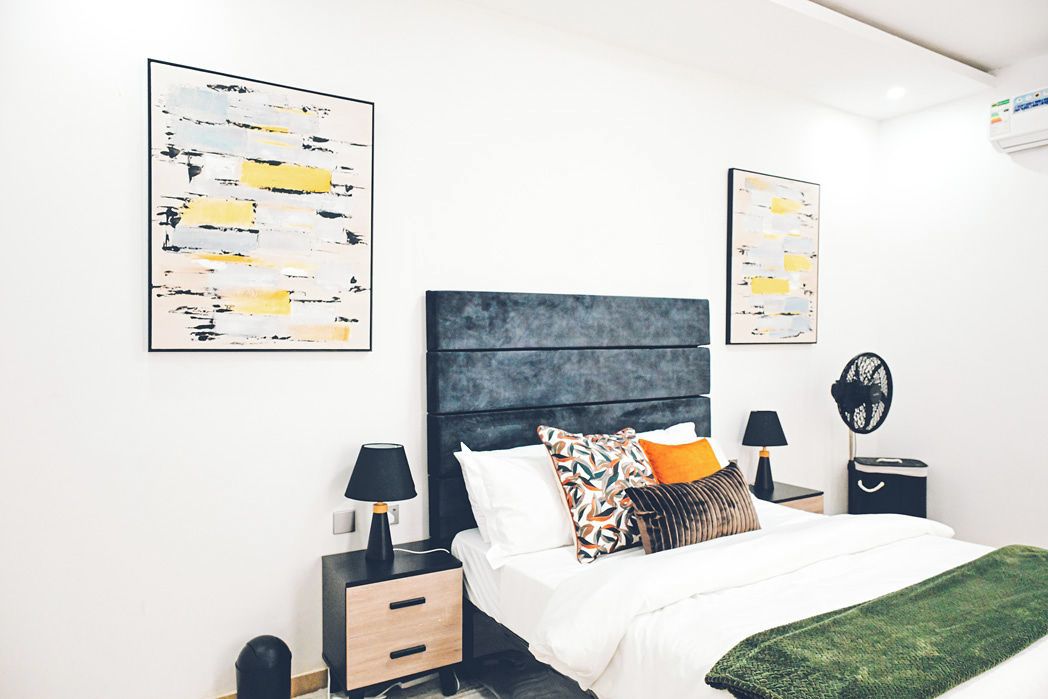 A modern bedroom with a bed, two bedside tables, and artwork on the walls.