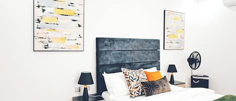 A modern bedroom with a bed, two bedside tables, and artwork on the walls.