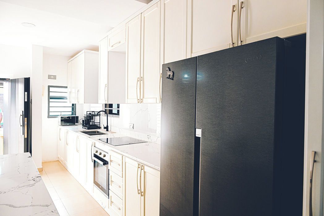 A modern kitchen with white cabinetry, a black refrigerator, and stainless steel appliances.