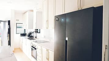 A modern kitchen with white cabinetry, a black refrigerator, and stainless steel appliances.