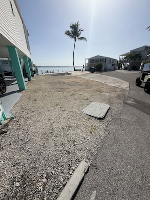 A gravel area with a manhole cover, a palm tree, and a building with a balcony.