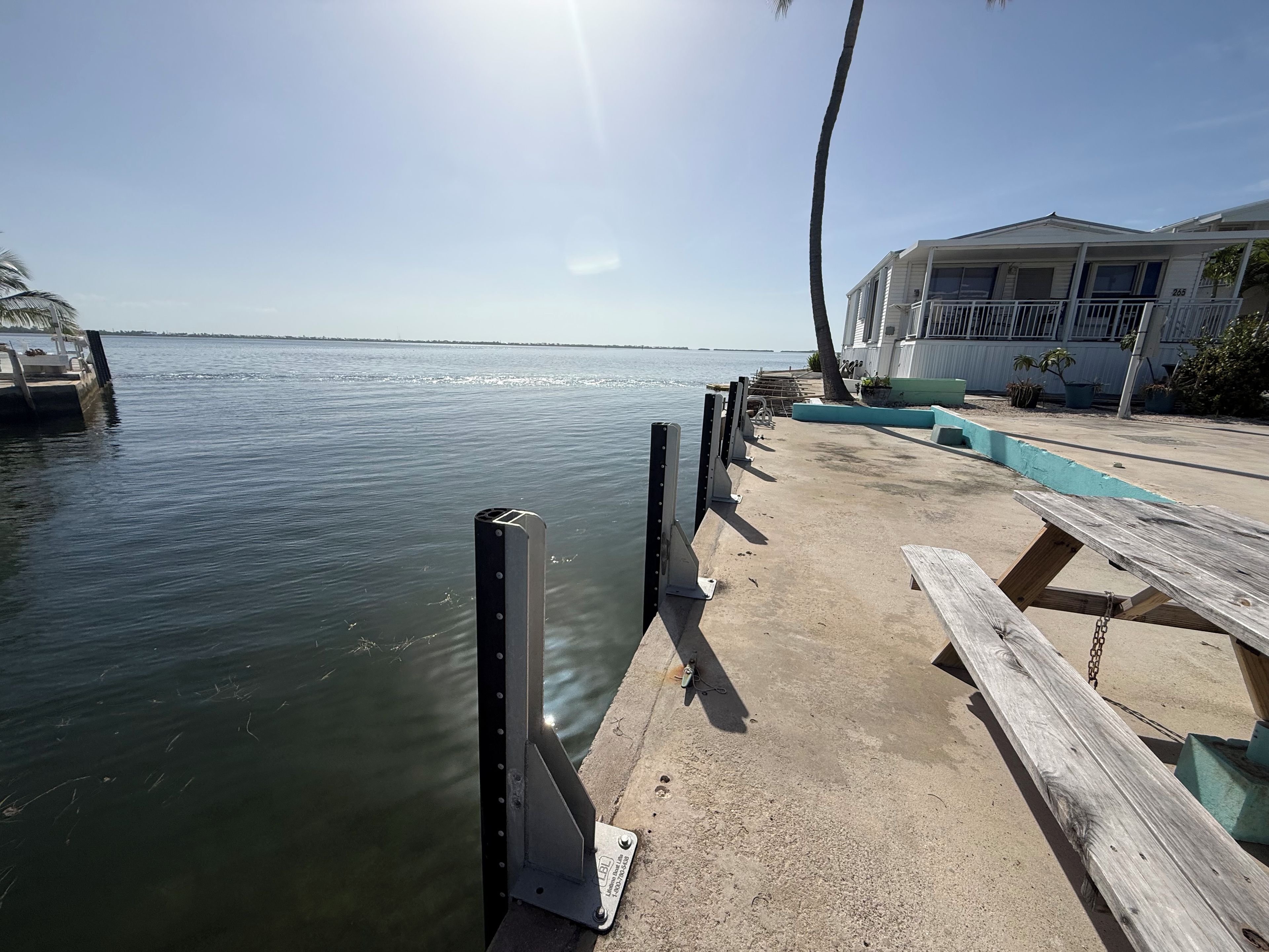 A waterfront dock with a wooden bench and a metal railing.