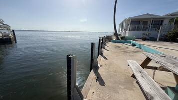 A waterfront dock with a wooden bench and a metal railing.