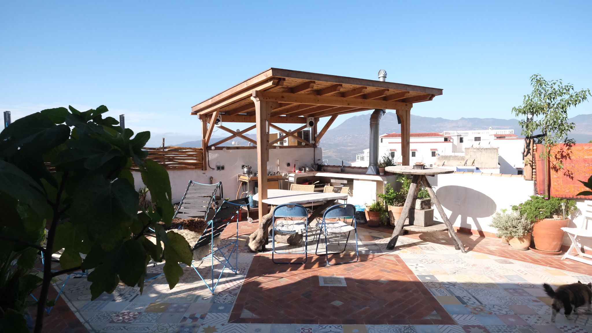 Une terrasse sur le toit agrémentée d’une pergola en bois, de sièges d’extérieur et de plantes en pot.