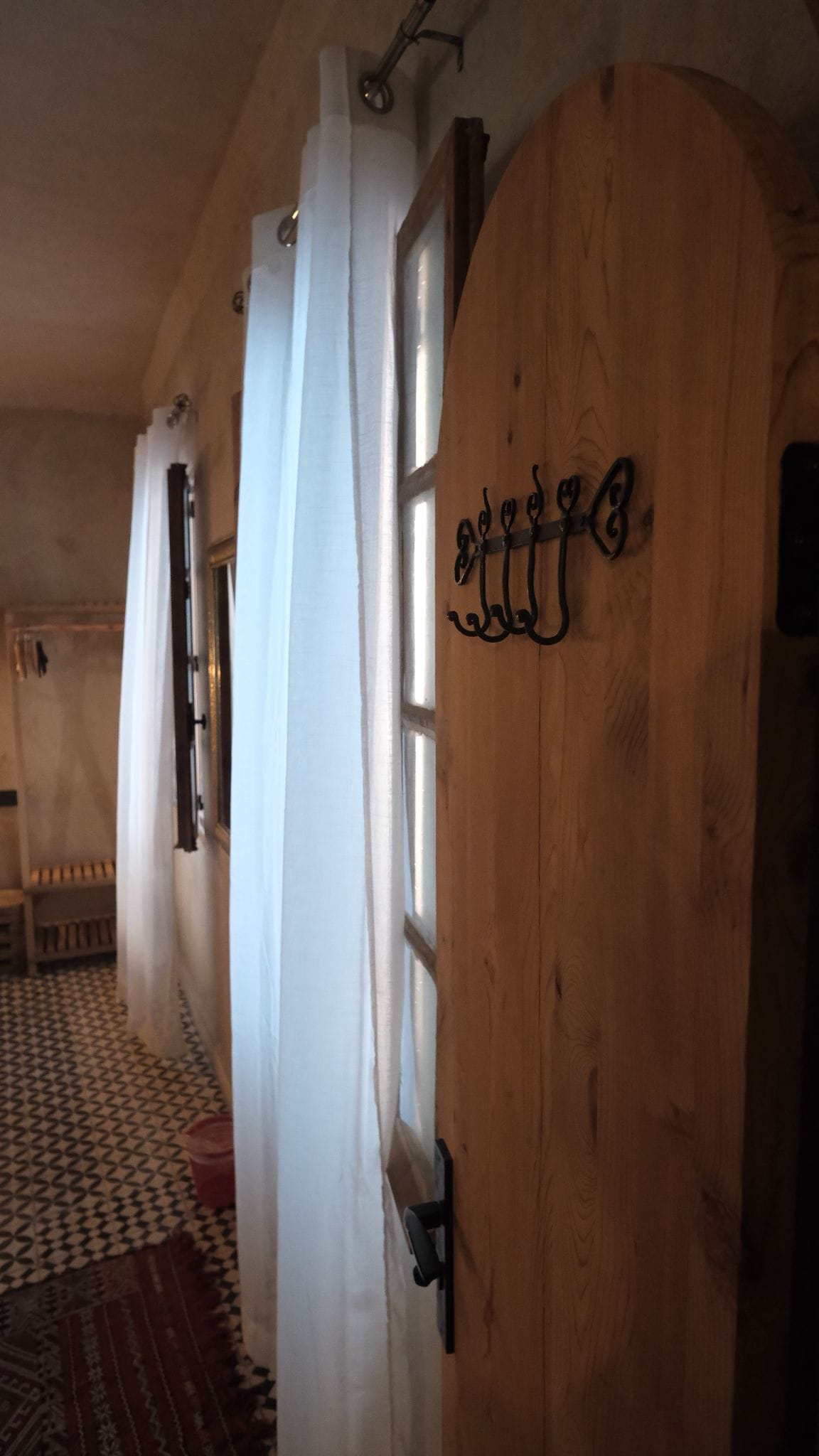 A hallway with a wooden door, a coat rack, and a patterned floor.