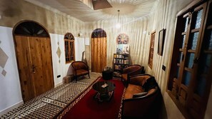 A room with a patterned carpet, wooden doors, a bookshelf, and leather armchairs. - Auberge Nautilus (Chefchaouen)