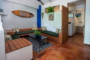 A living area with a sofa, coffee table, and a decorative surfboard. - Villas Jacquelina (Quepos)
