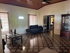 Una sala de estar con un sofá, una mesa de centro, piso estampado y un aparador.
