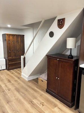 A room with a wooden cabinet, a white staircase, and a lamp.