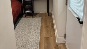Una camera da letto con un letto, una scrivania, un tappeto e una finestra con persiane.