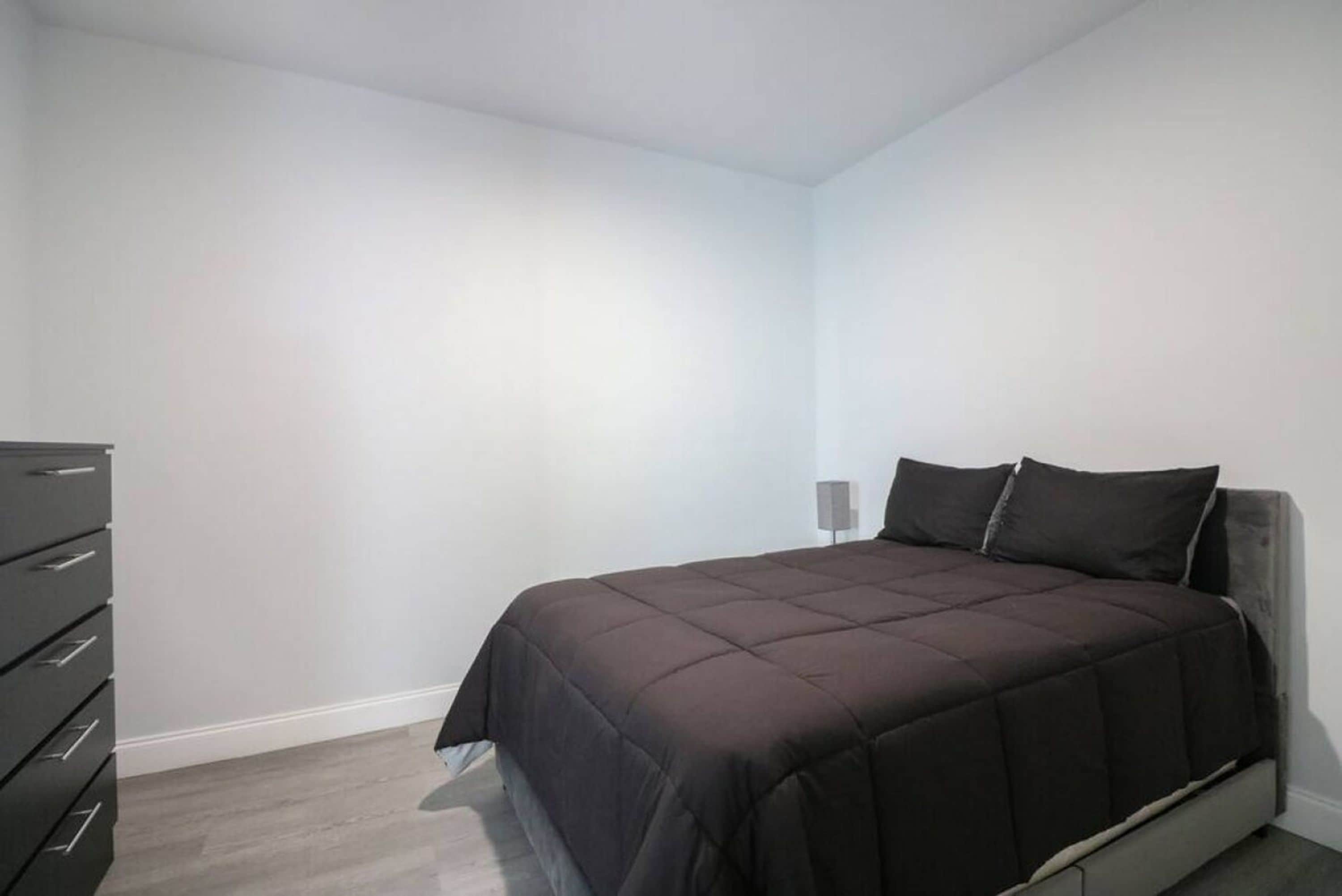 A bedroom with a bed, a dresser, and a nightstand.