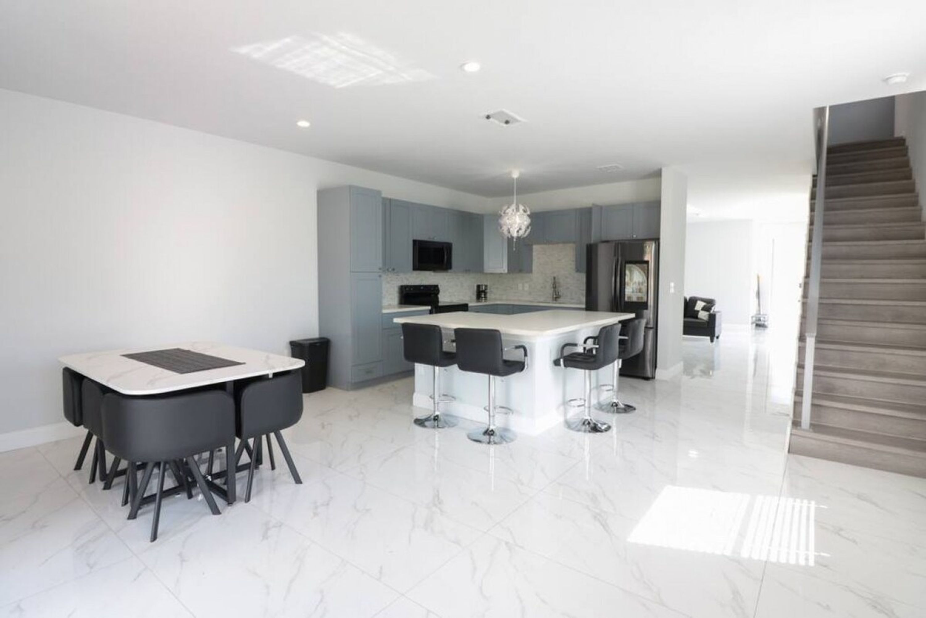 Cozinha moderna com ilha central, banquetas e área de refeições com mesa e cadeiras.
