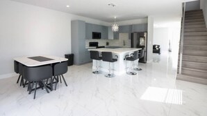 Cozinha moderna com ilha central, banquetas e área de refeições com mesa e cadeiras.
