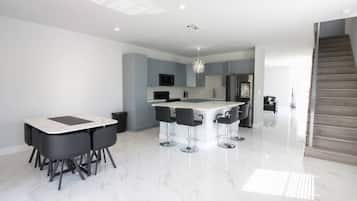 Cozinha moderna com ilha central, banquetas e área de refeições com mesa e cadeiras.