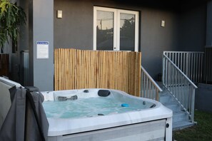 A hot tub in a backyard with a wooden fence, a metal railing, and a sign with safety rules. - Luxury 4BR Miami Villa With Hot Tub and Gazebo (Miami)