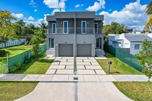A two-story building with a symmetrical facade, two garage doors, and a central entrance with steps. - Luxury 4BR Miami Villa With Hot Tub and Gazebo (Miami)