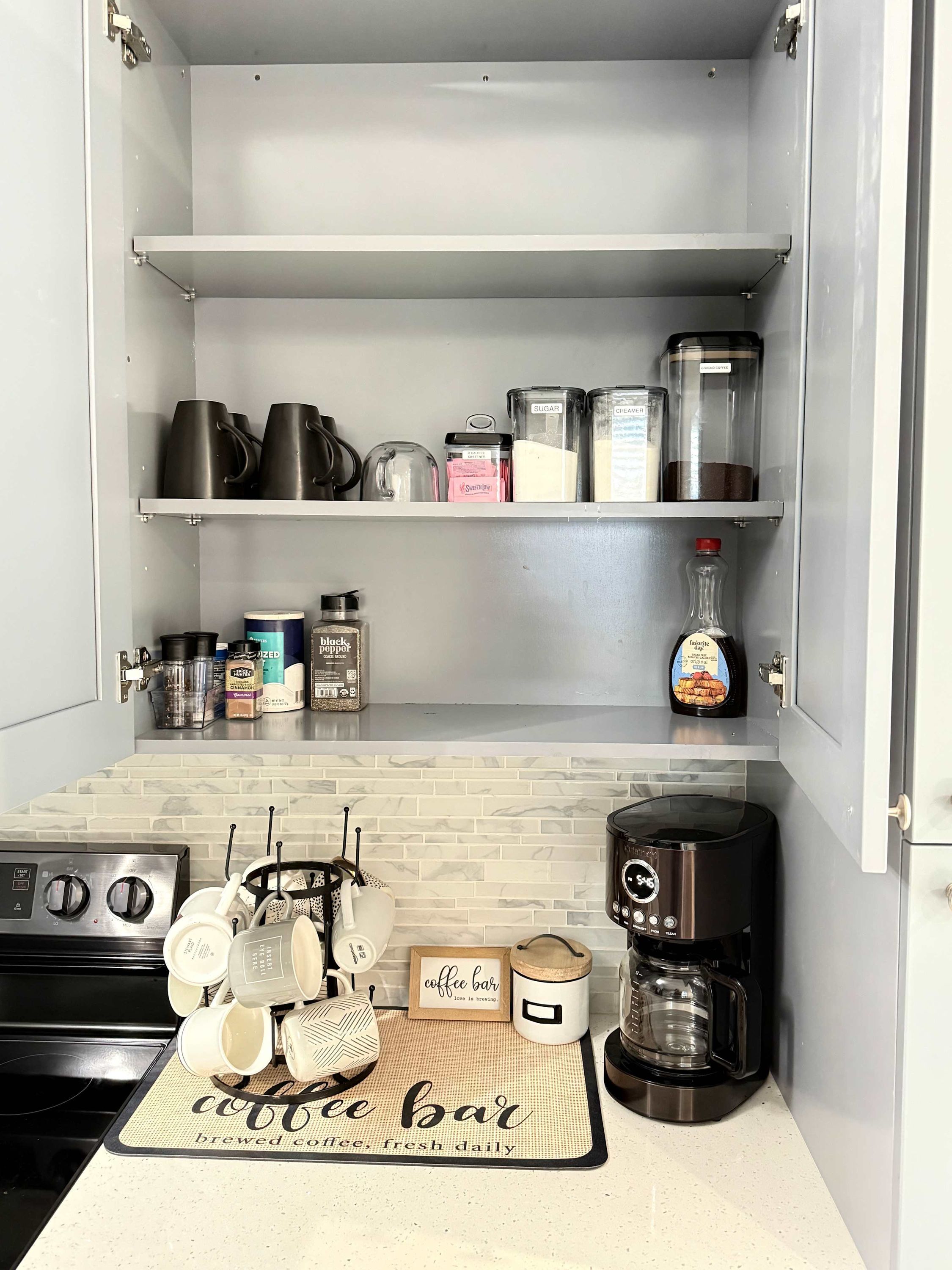 Eine Küche mit einer Kaffeebar, einschließlich einer Kaffeemaschine, Tassen und einer Unterlage mit Kaffeemotiv.