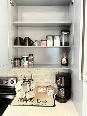 A kitchen with a coffee bar area, including a coffee maker, mugs, and a coffee-themed placemat. - Luxury 4BR Miami Villa With Hot Tub and Gazebo (Miami)