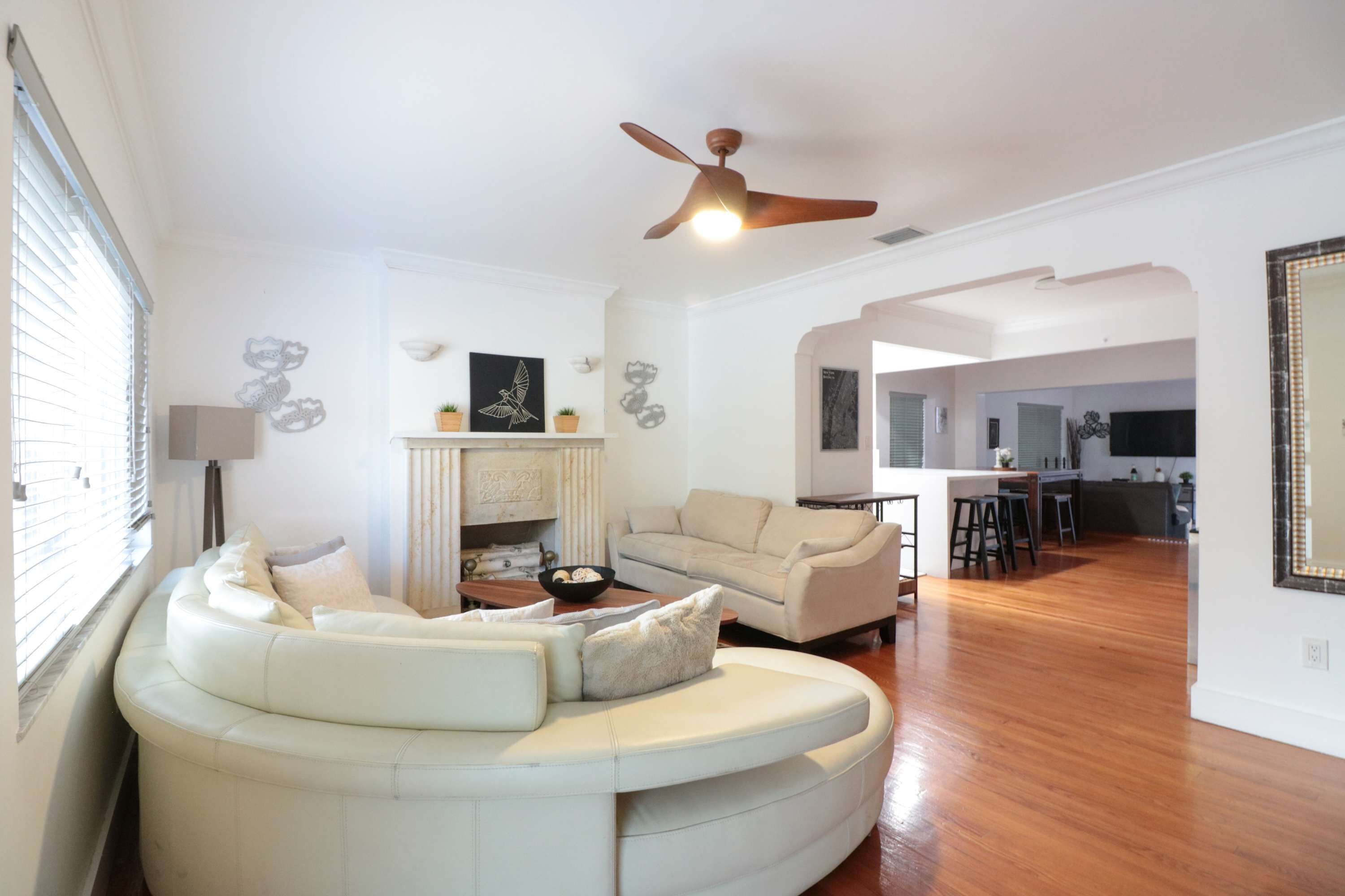 A living room with a curved white sofa, a fireplace, and a ceiling fan.