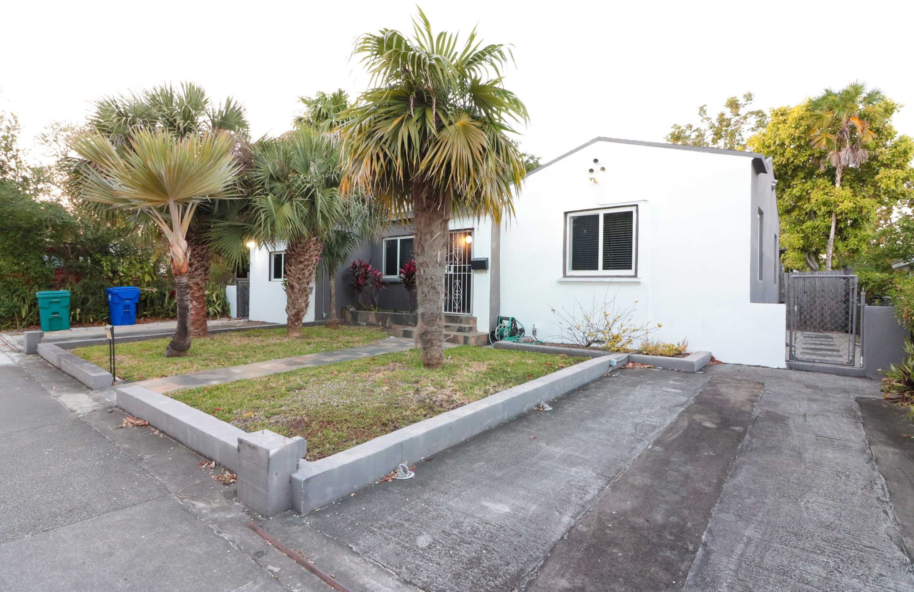 A single-story house with a small front yard, a garage, and a gated driveway.