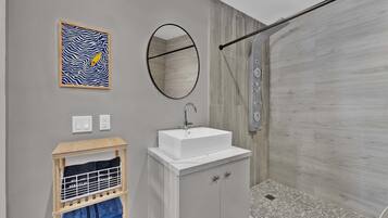 A modern bathroom with a shower, a sink, a mirror, and a towel rack.