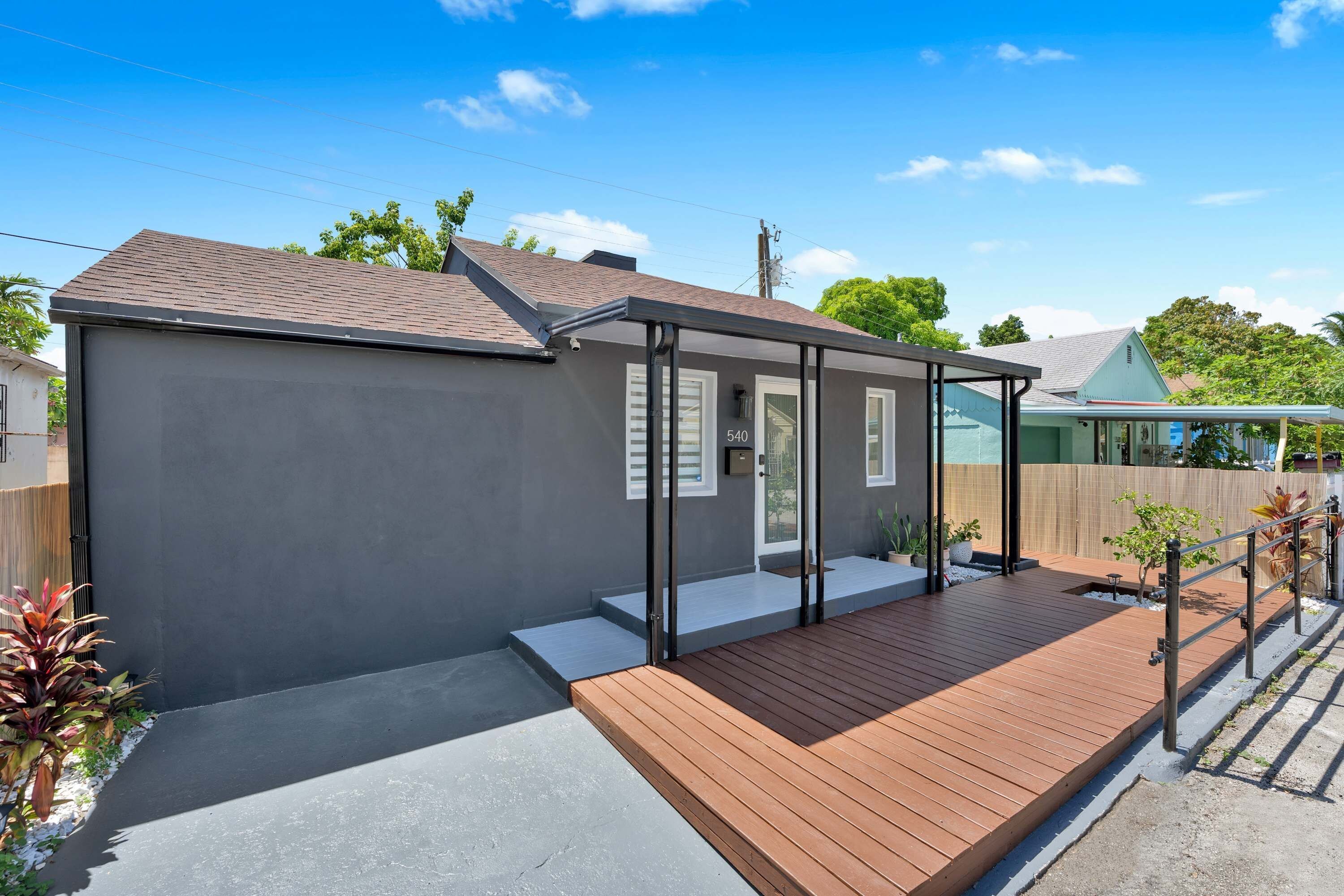 A modern house with a grey exterior, a wooden deck, and a small porch area.