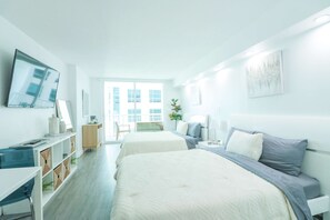 A modern hotel room with two beds, a TV, a desk, and a view of the city. - Chill Studio Getaway Luxury Brickell High Rise (Miami)