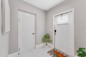 A hallway with two white doors, a small potted plant, and a patterned rug on the floor. - Modern 4BR Villa Near Hollywood Beach FTL (Hollywood)