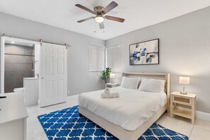 A bedroom with a bed, bedside tables, a ceiling fan, a shower, and a bathroom. - Modern 4BR Villa Near Hollywood Beach FTL (Hollywood)