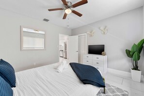 A bedroom with a bed, a ceiling fan, a TV, a dresser, and a plant. - Modern 4BR Villa Near Hollywood Beach FTL (Hollywood)