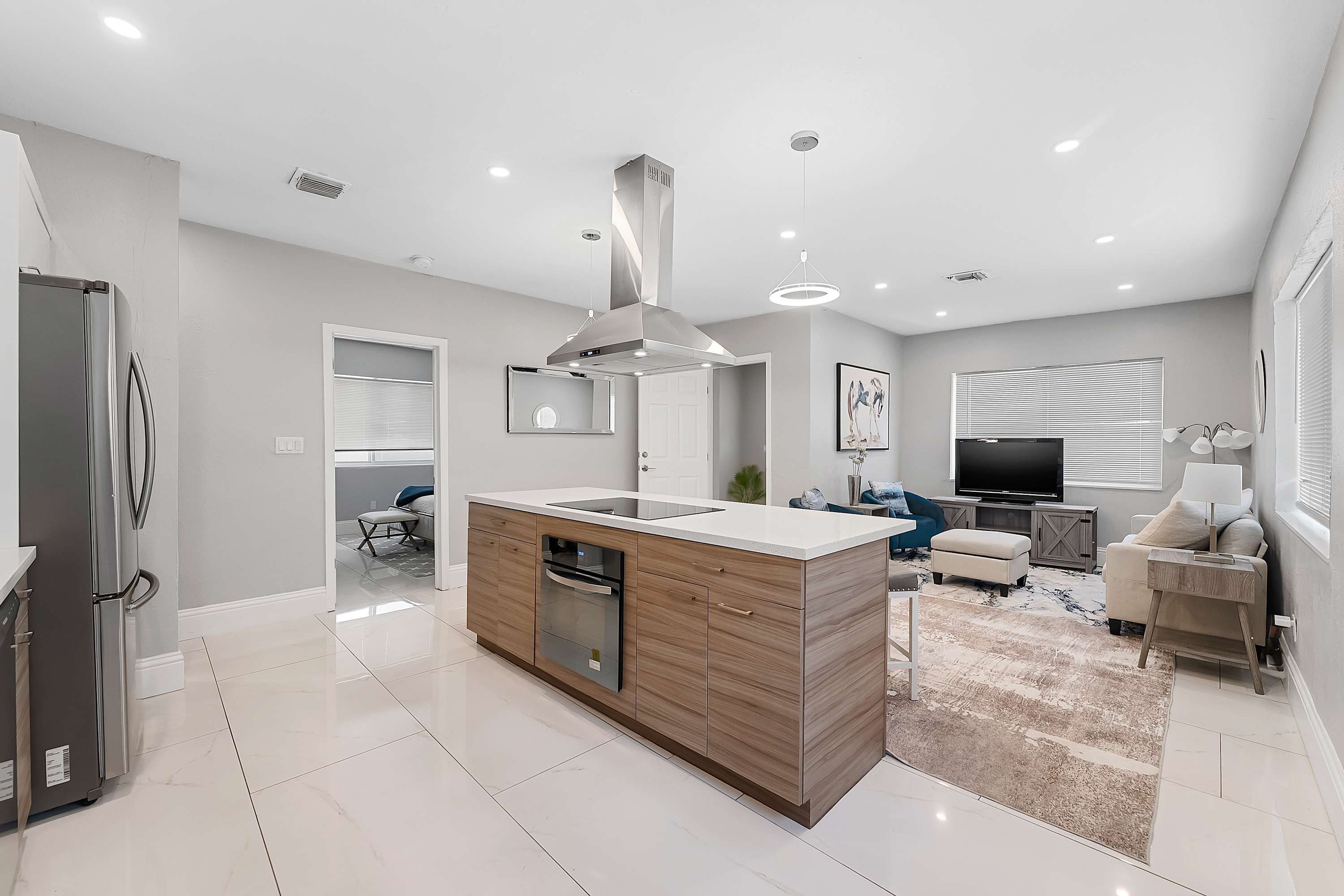 A modern kitchen with a central island, built-in appliances, and a dining area with a TV.