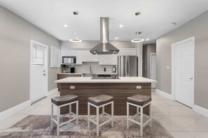 A modern kitchen with a central island, stainless steel appliances, and bar stools. - Modern 4BR Villa Near Hollywood Beach FTL (Hollywood)