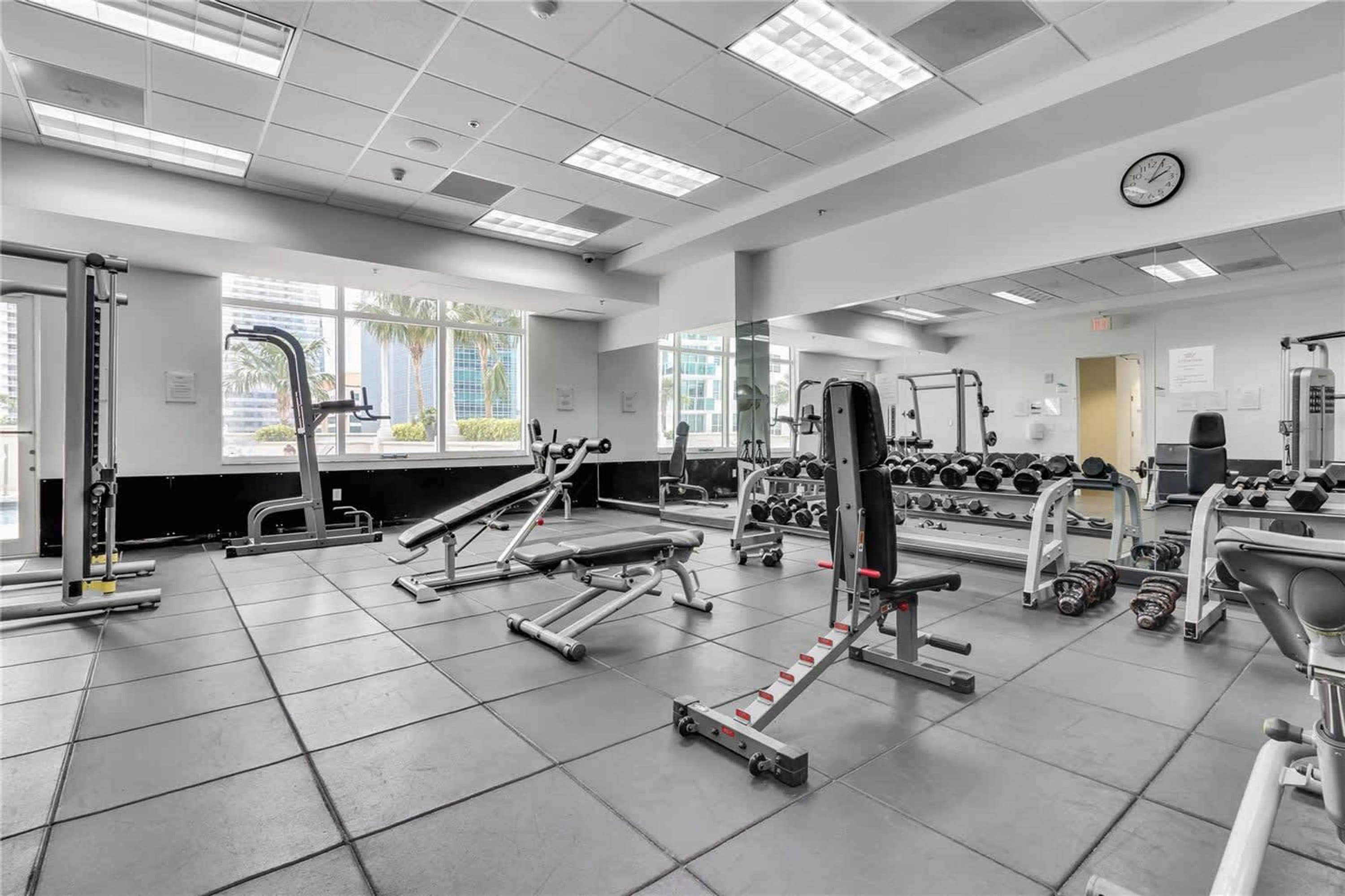 A gym with various exercise equipment, including treadmills, weight machines, and dumbbells.