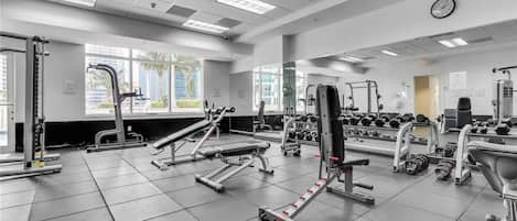 Une salle de sport équipée de divers appareils d’exercice, notamment des tapis de course, des appareils de musculation et des haltères.