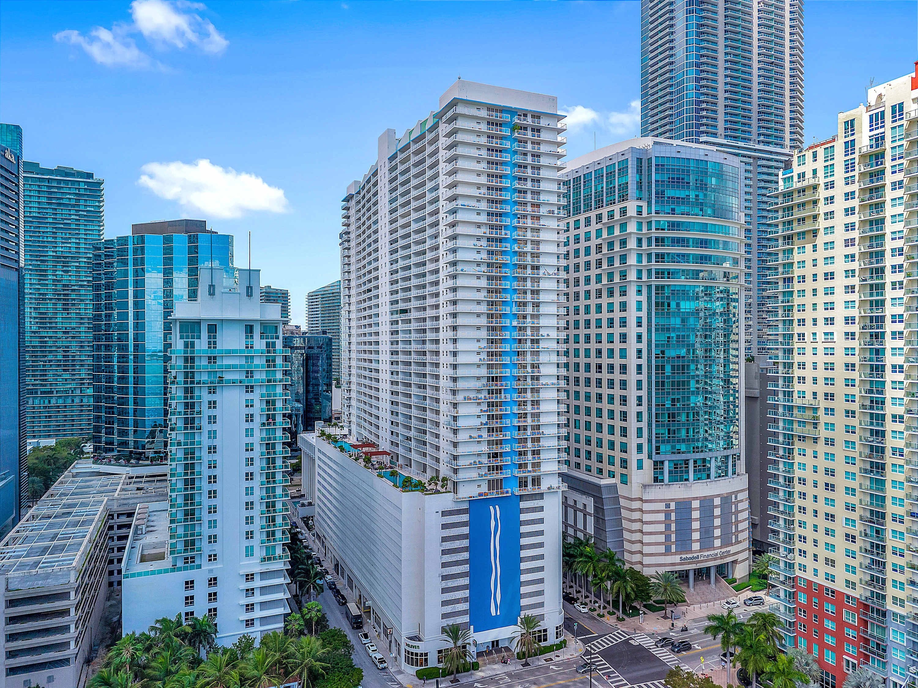 A high-rise building with multiple floors, large windows, and a prominent blue vertical stripe.