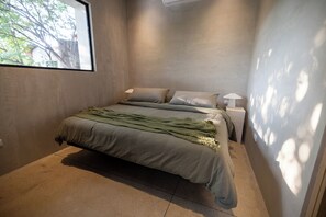 Un dormitorio con una cama, dos mesitas de noche y un ventanal.