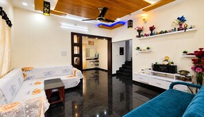 Ein modernes Wohnzimmer mit einer Couch, einem Couchtisch, einem Fernseher und einer Treppe, die zu einer oberen Etage führt.
