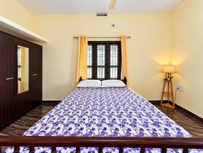 Ein Schlafzimmer mit einem Bett, Vorhängen, einer Stehlampe und einem Kleiderschrank.