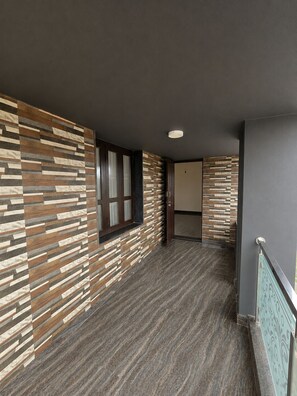 A hallway with a patterned wall, a window, and a door leading to another room.