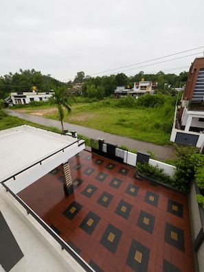 A rooftop terrace with a patterned floor, a palm tree, and a view of surrounding buildings.
