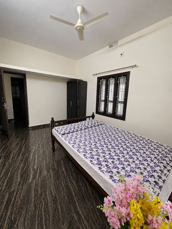 A bedroom with a bed, wardrobe, and a ceiling fan.