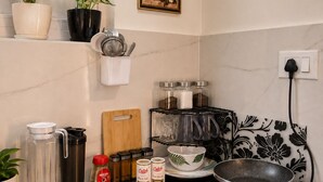 Een keuken met een koffiezetapparaat, een koekenpan, een snijplank en een kruidenrek.